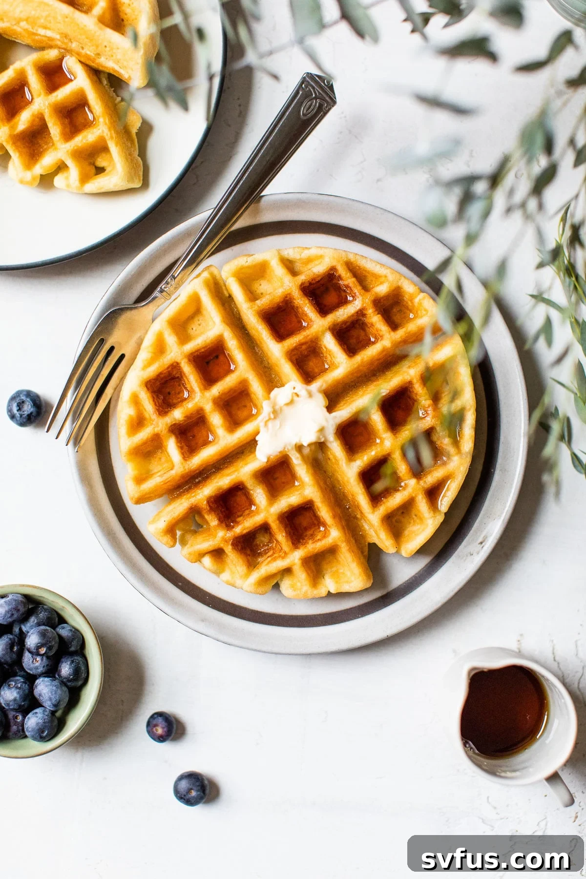 Golden-brown Paleo Waffle with a pat of butter melting on top, served on a white plate, ready for breakfast