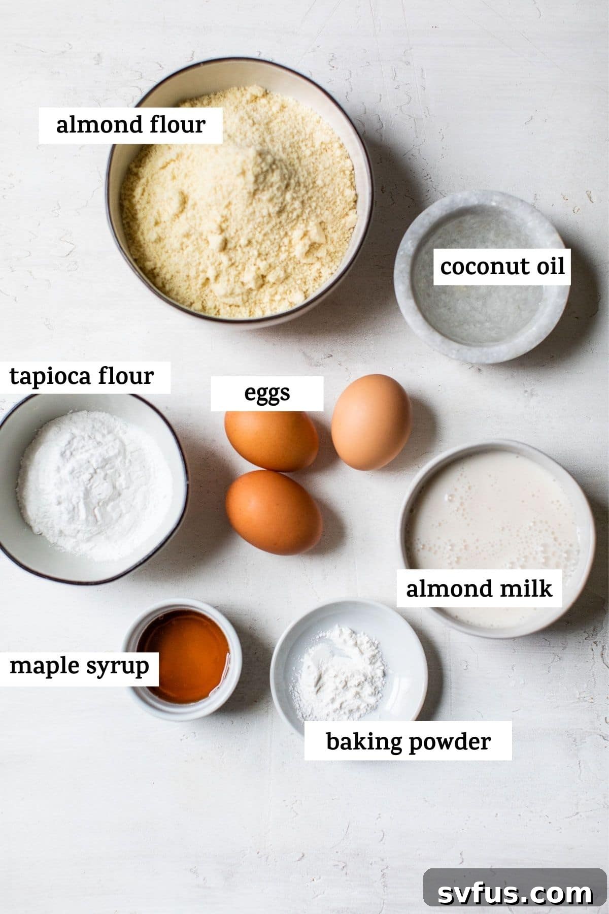Close-up shot of various ingredients laid out for paleo waffle preparation, including almond flour, tapioca flour, eggs, and coconut oil.