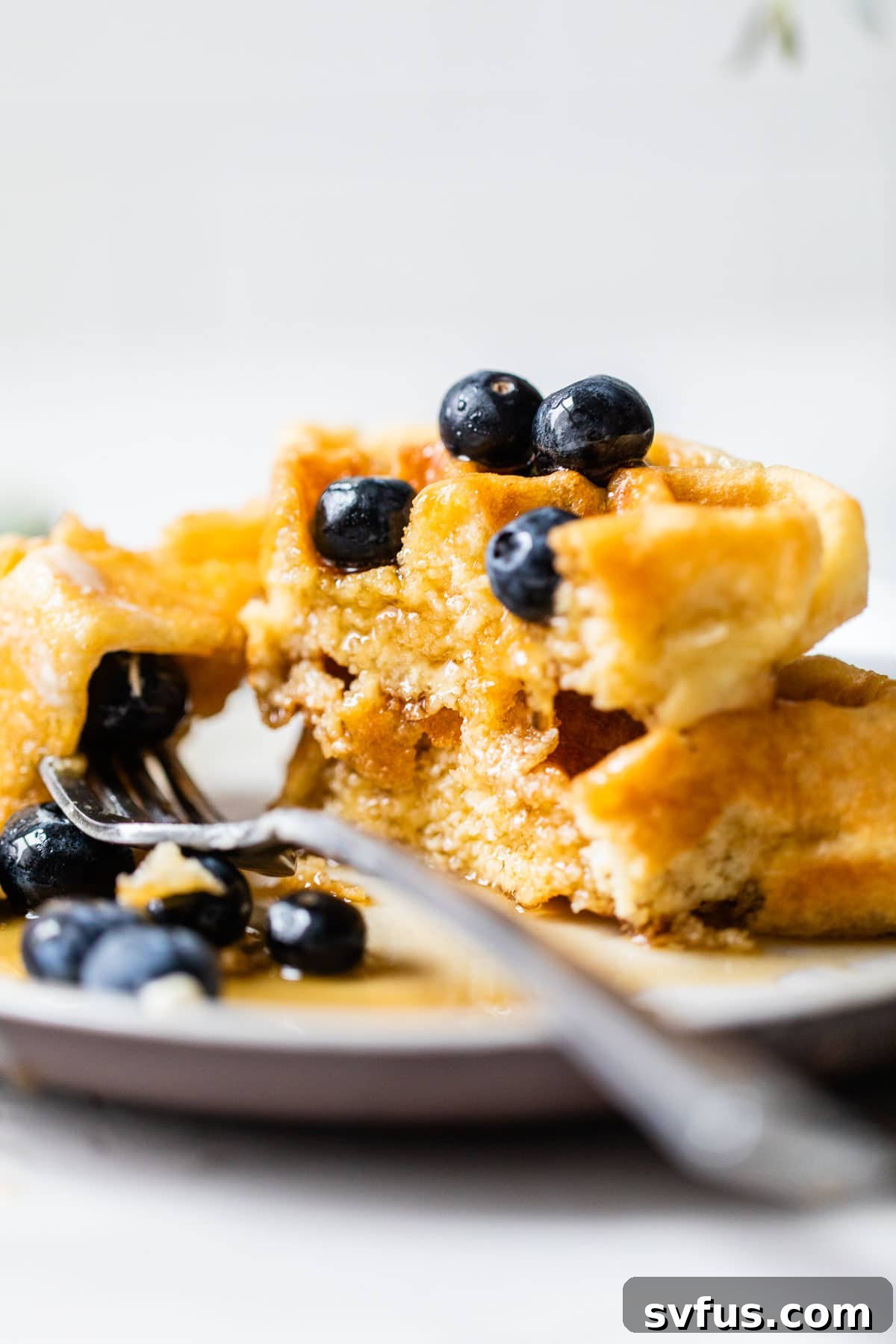 Fluffy paleo waffles topped generously with fresh blueberries and a drizzle of maple syrup.