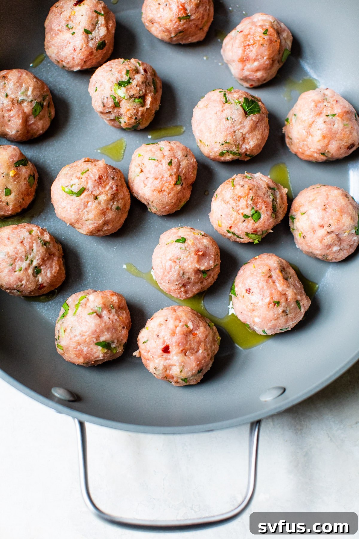 Raw paleo turkey meatballs neatly arranged in a skillet before cooking, showcasing their pre-searing appearance.
