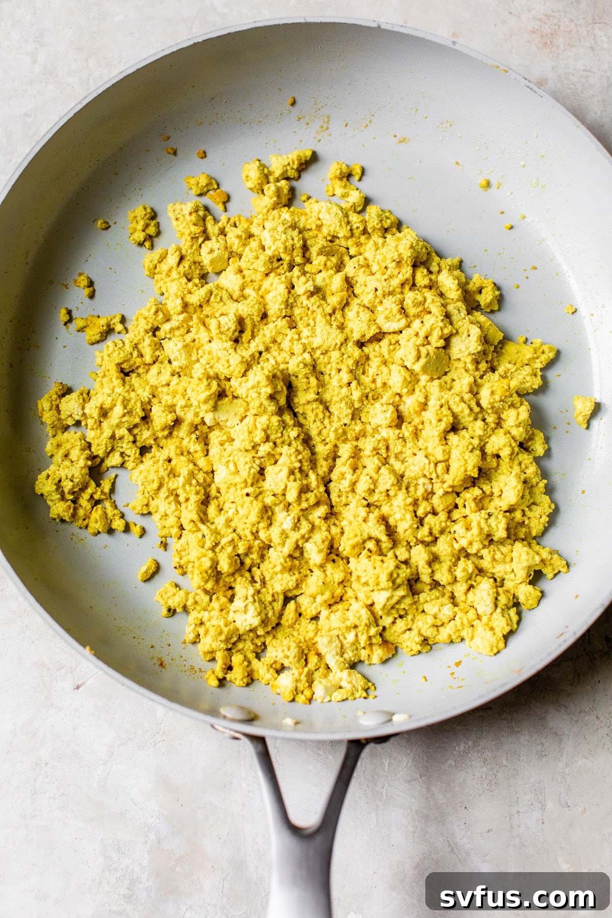 A vibrant and perfectly seasoned tofu scramble, rich in color and texture, filling a large skillet and ready to be served for a delicious vegan breakfast.