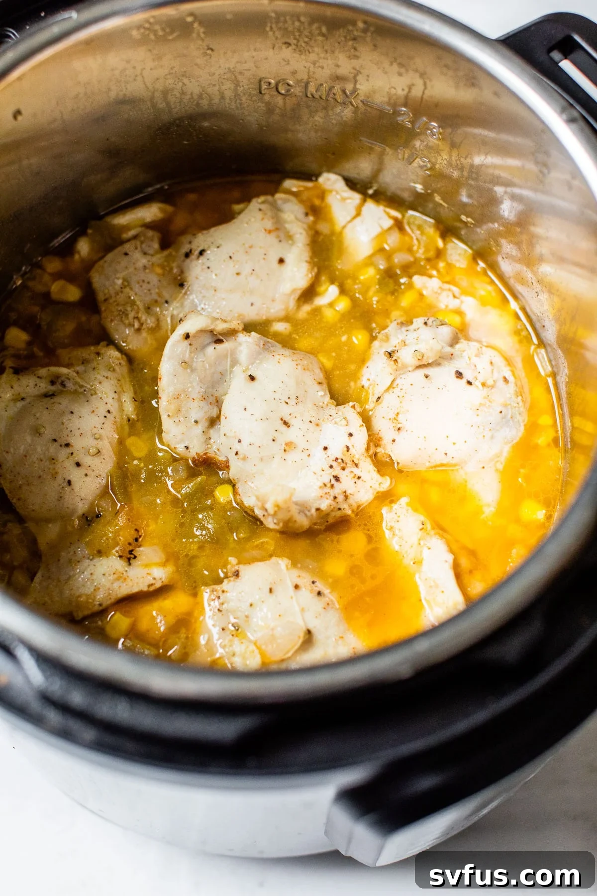 Cooked chicken submerged in a flavorful broth inside the Instant Pot after pressure cooking, ready to be removed and shredded.