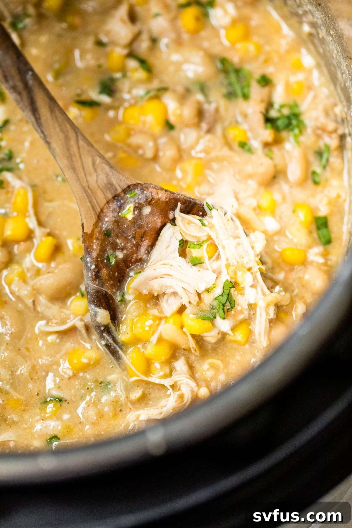 The Instant Pot now contains shredded chicken mixed into the creamy corn and bean chili, fully combined and ready for serving.