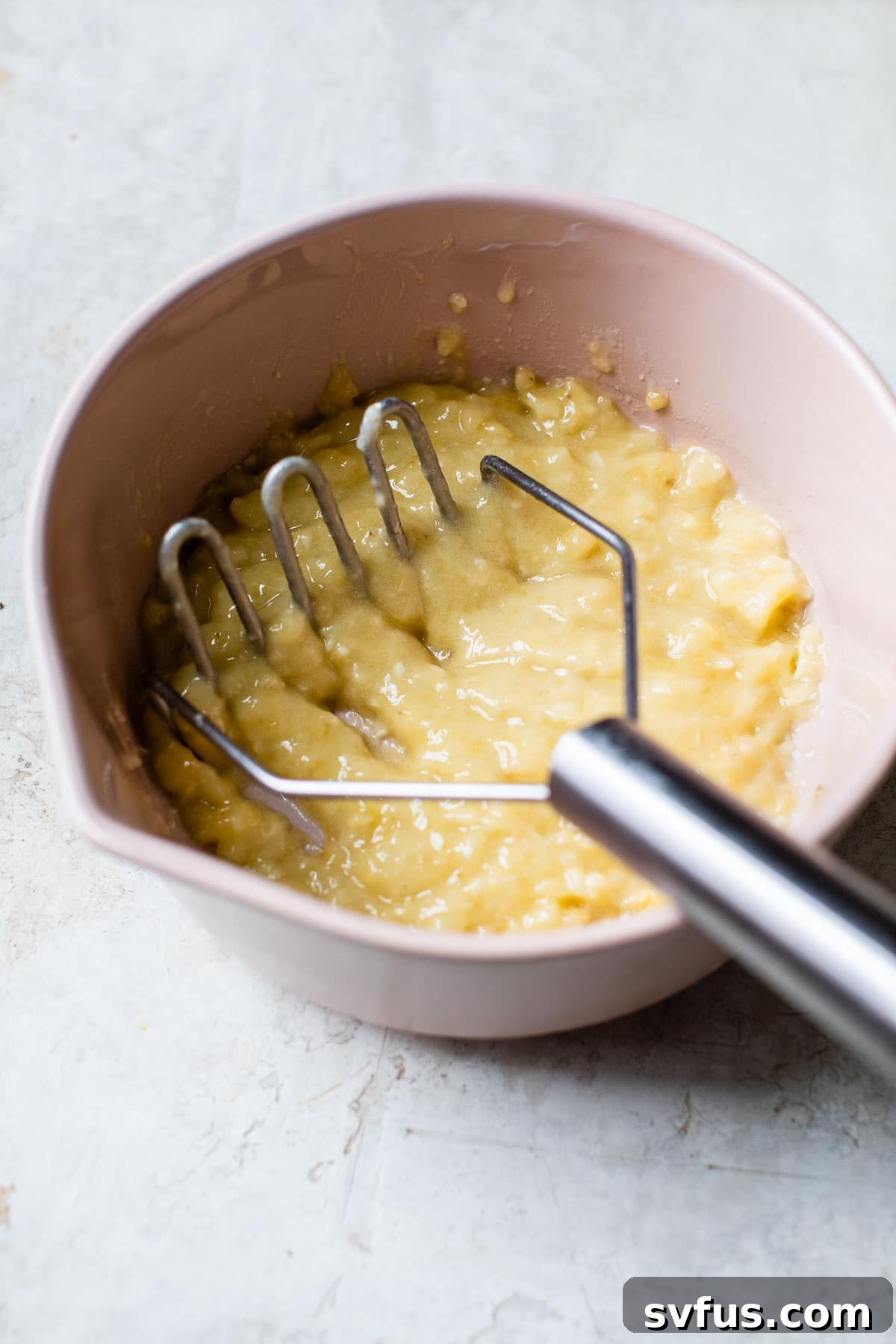 Mashed ripe bananas in a large bowl, ready for the next ingredients.