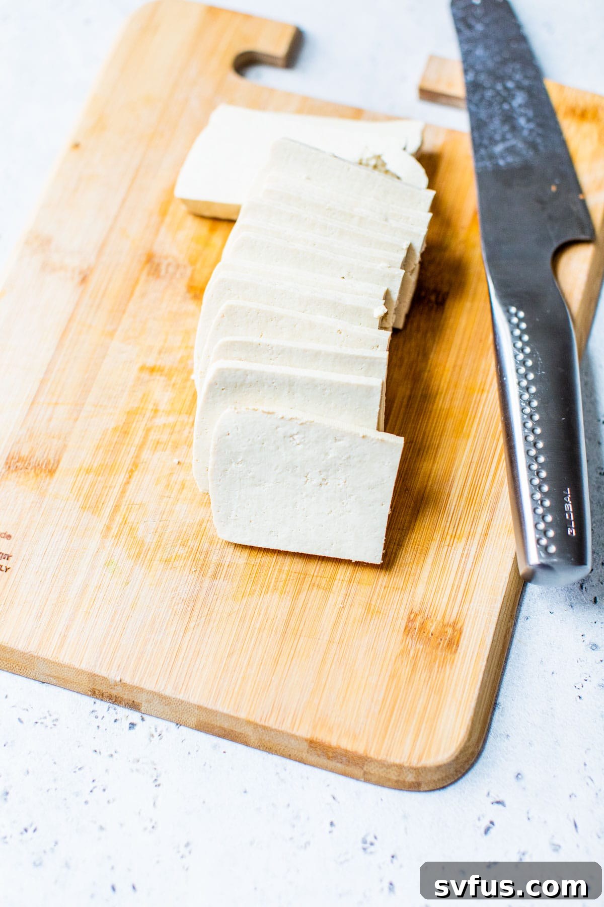 Carefully sliced blocks of extra-firm tofu arranged on a cutting board, ready for marinating and cooking, showcasing their uniform shape.