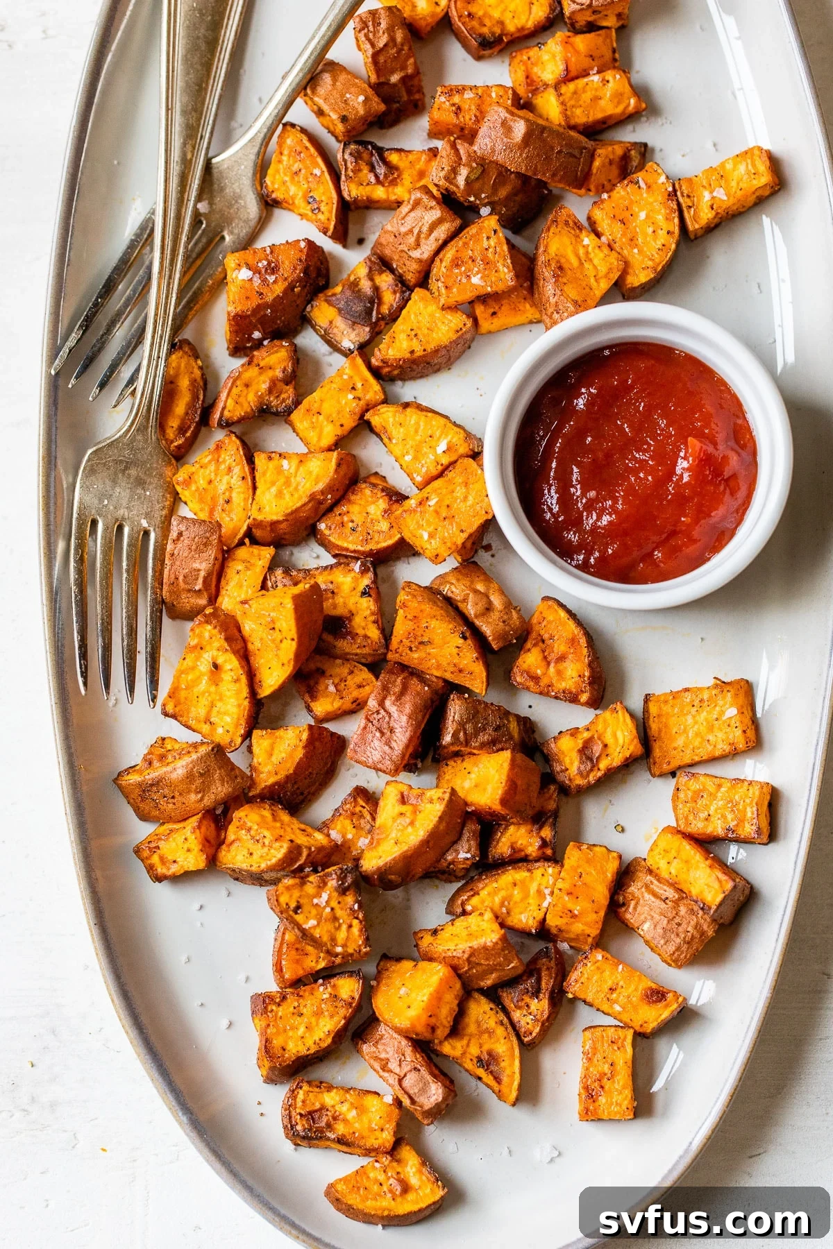 cooked sweet potatoes on a plate with a side of ketchup