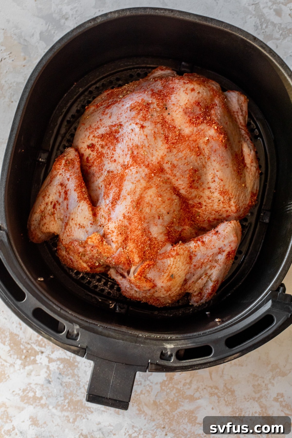 raw whole chicken placed inside an air fryer