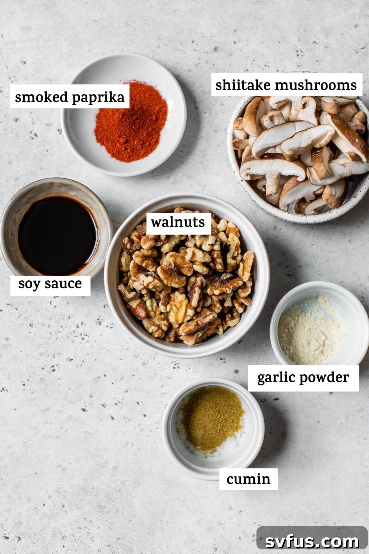 A collection of fresh ingredients for walnut taco meat including walnuts, shiitake mushrooms, and various spices arranged on a rustic wooden board.