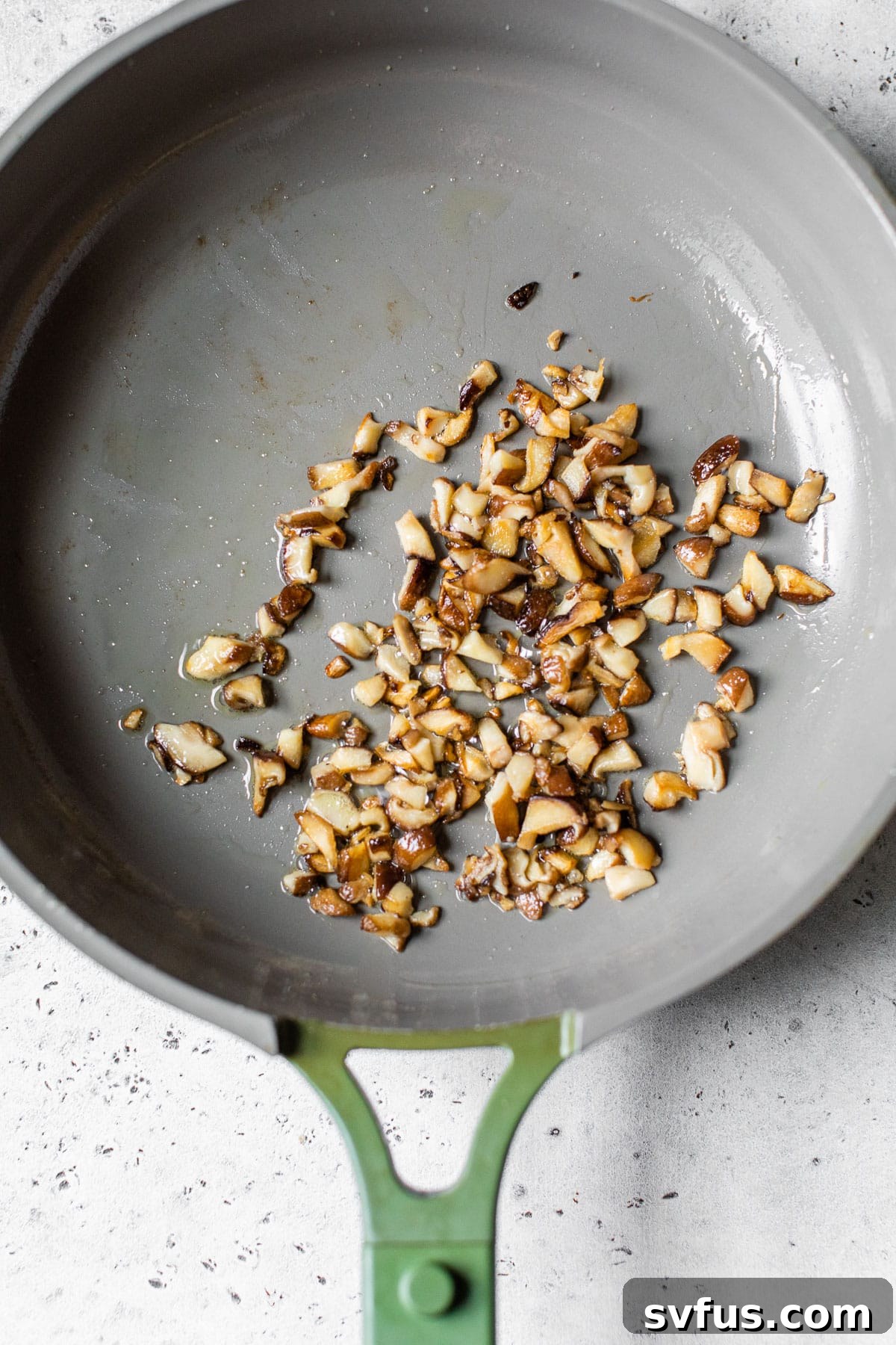 Perfectly cooked diced mushrooms sizzling in a skillet, ready to be combined with the walnut mixture.
