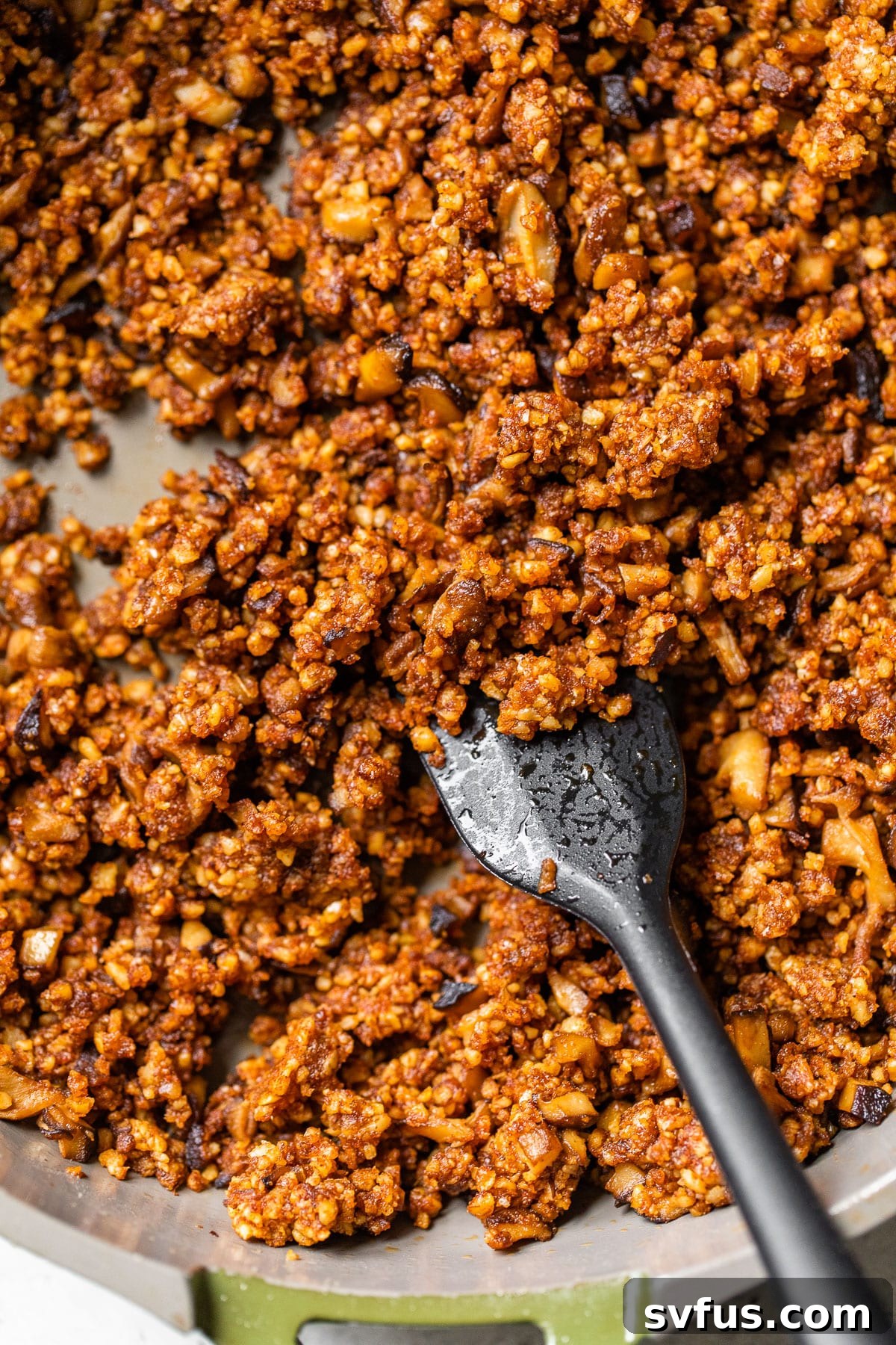 A close-up shot of cooked shiitake mushrooms and seasoned walnuts expertly blended in a skillet, showcasing the perfect texture of the vegan taco meat.