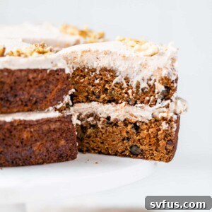 A slice of vegan carrot cake with a portion removed, emphasizing its perfect texture and frosting.
