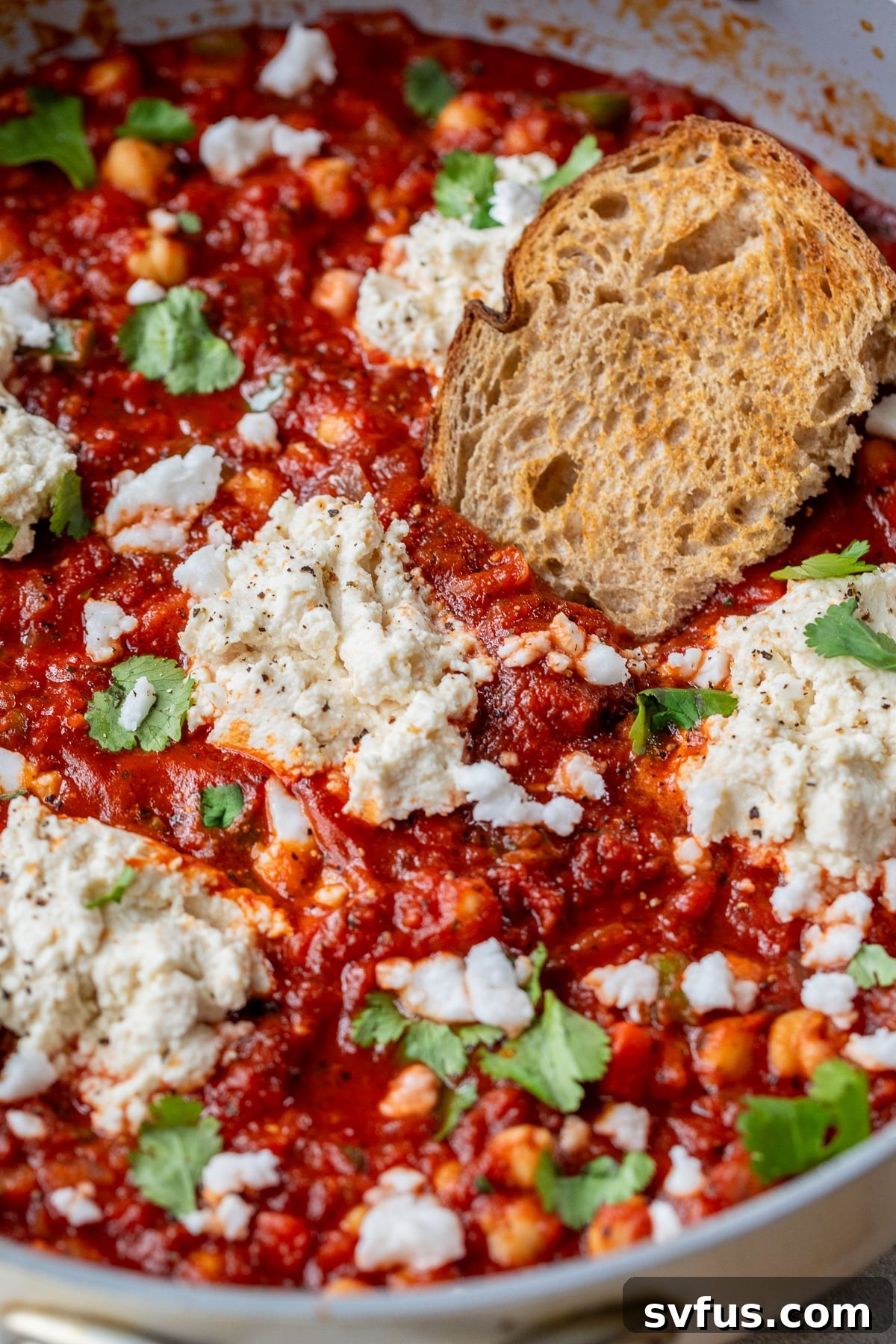 Close-up of a perfectly portioned serving of vegan shakshuka with a side of crusty bread, highlighting its appealing textures and rich colors