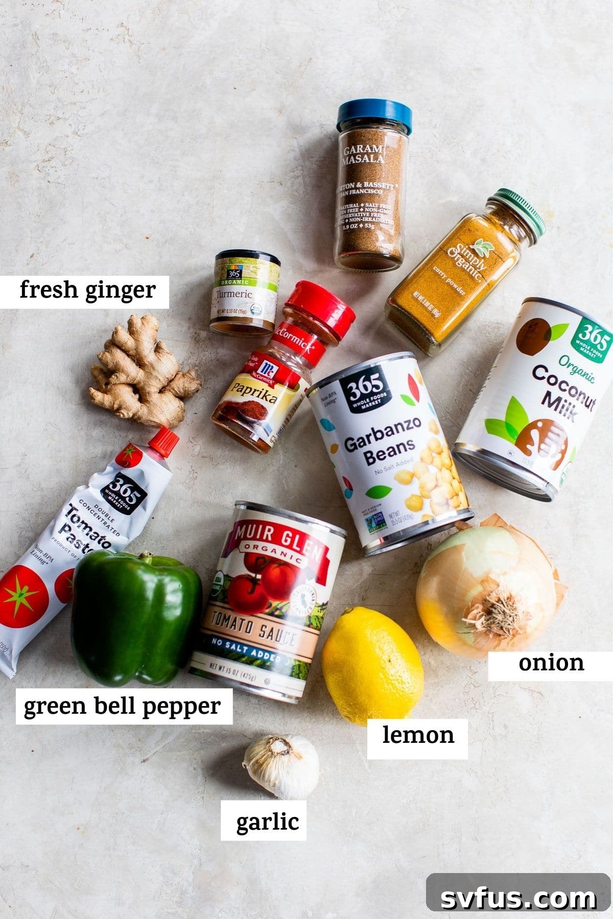 Various canned ingredients and whole spices arranged on a rustic wooden table, with a text overlay about preparing vegan tikka masala ingredients.