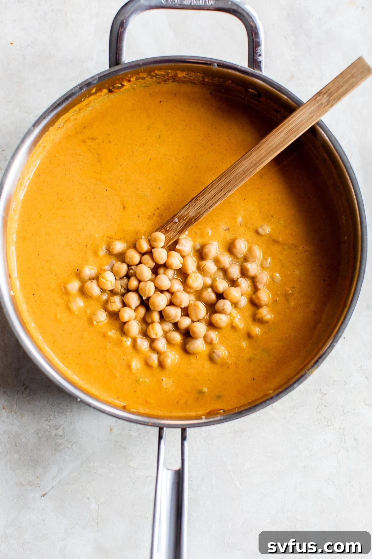 Hearty chickpeas immersed in a rich, orange-hued vegan tikka masala sauce, simmering gently in a skillet.