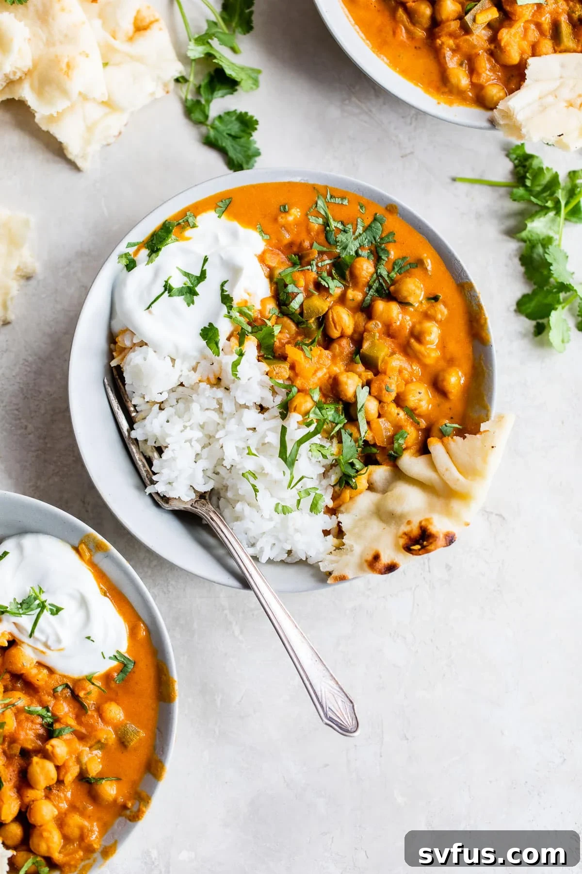 A perfectly portioned bowl of vegan chickpea tikka masala, served with white rice and a piece of naan bread, ready to be enjoyed.