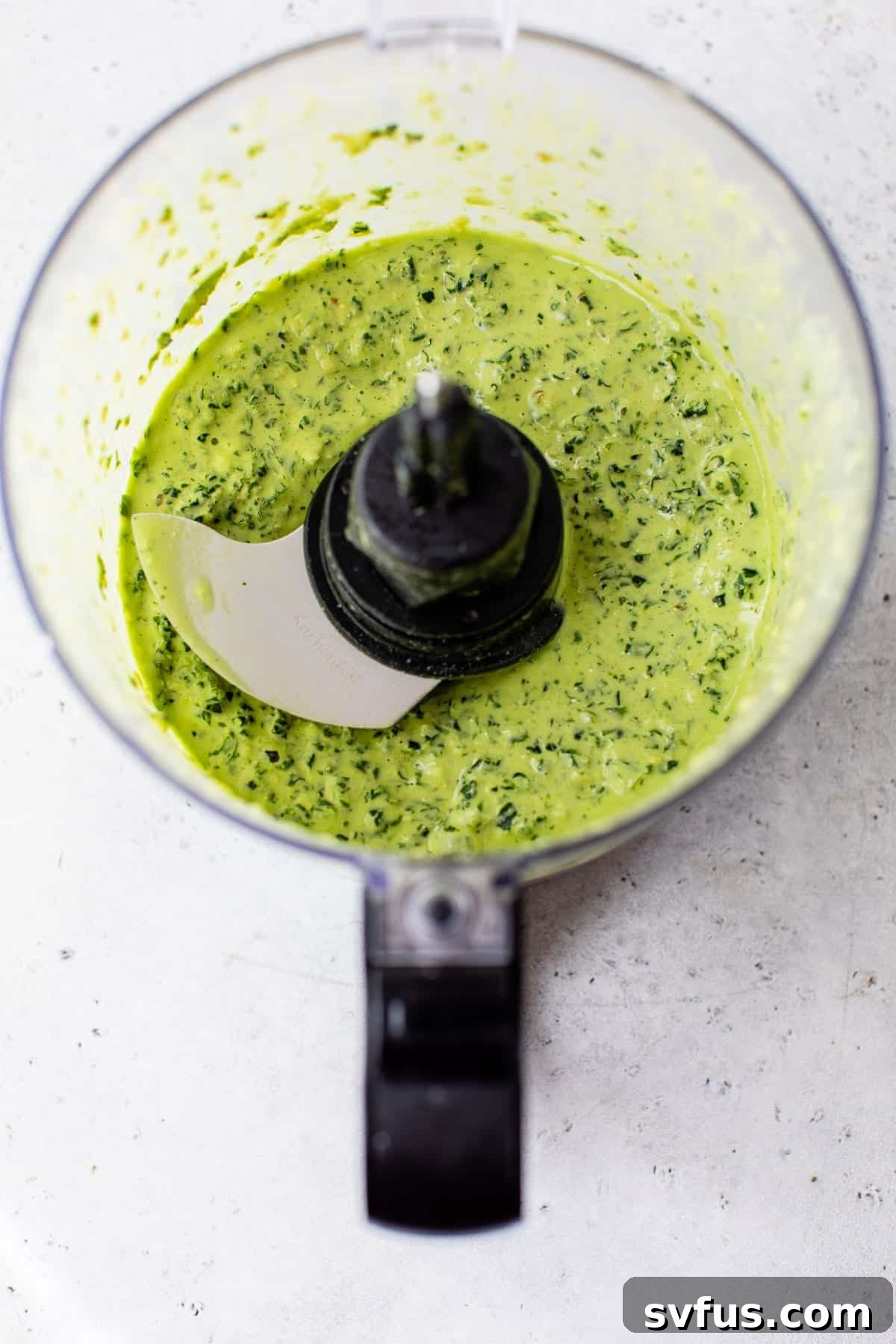 The blended, creamy kale pesto sauce in a food processor, ready for final seasoning.