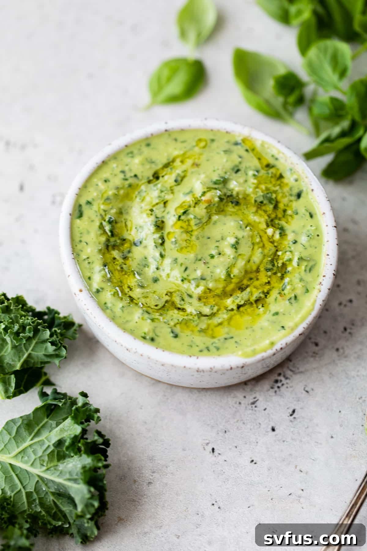 A beautifully presented bowl of kale pesto, freshly made and drizzled with a touch of olive oil, ready to be served.