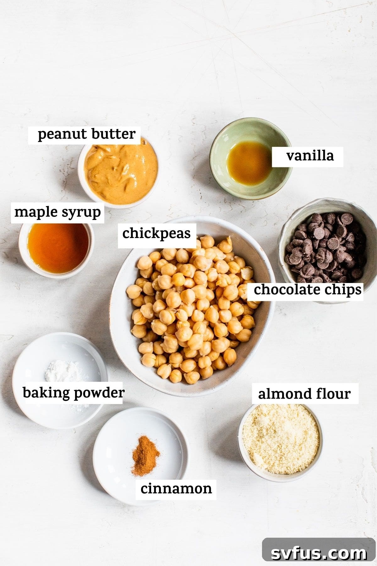 Bowls of ingredients for chickpea cookie dough, including chickpeas, peanut butter, almond flour, and chocolate chips.
