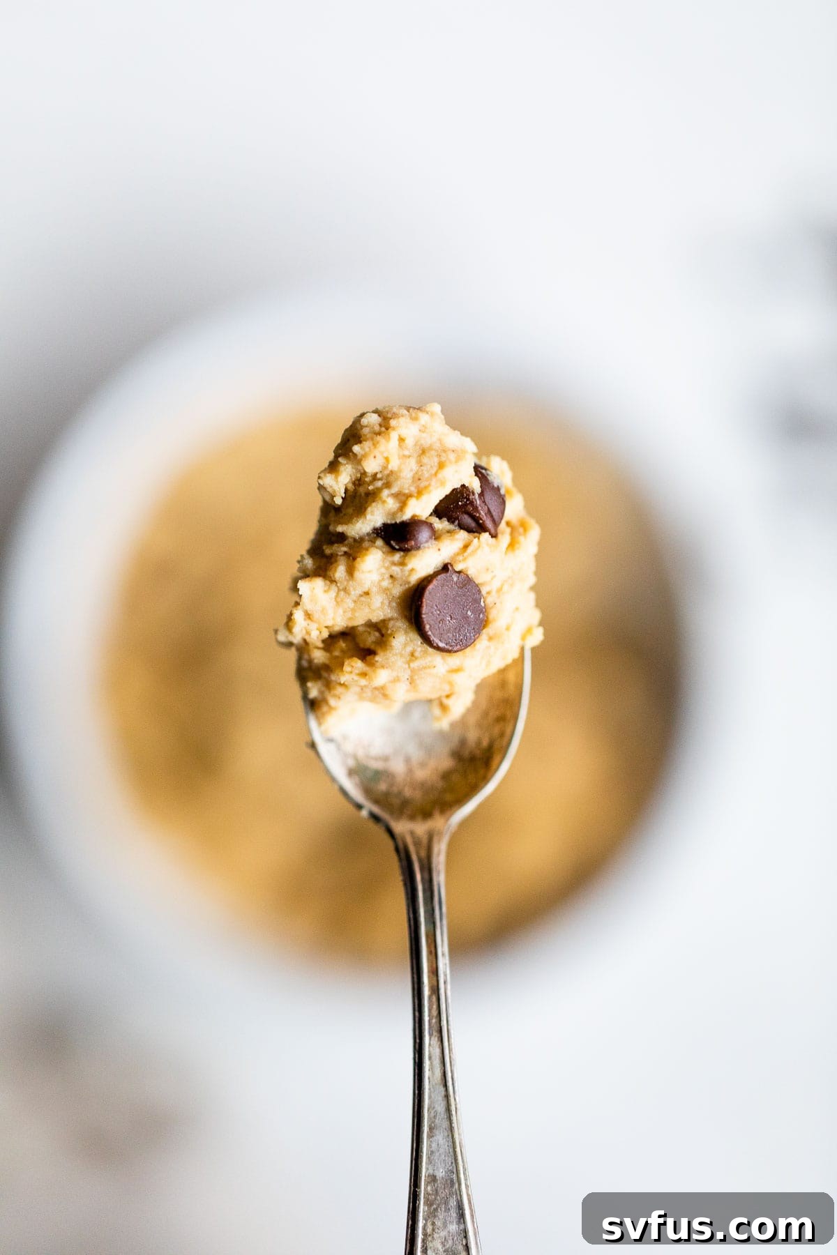 A spoon overflowing with creamy chickpea chocolate chip cookie dough.
