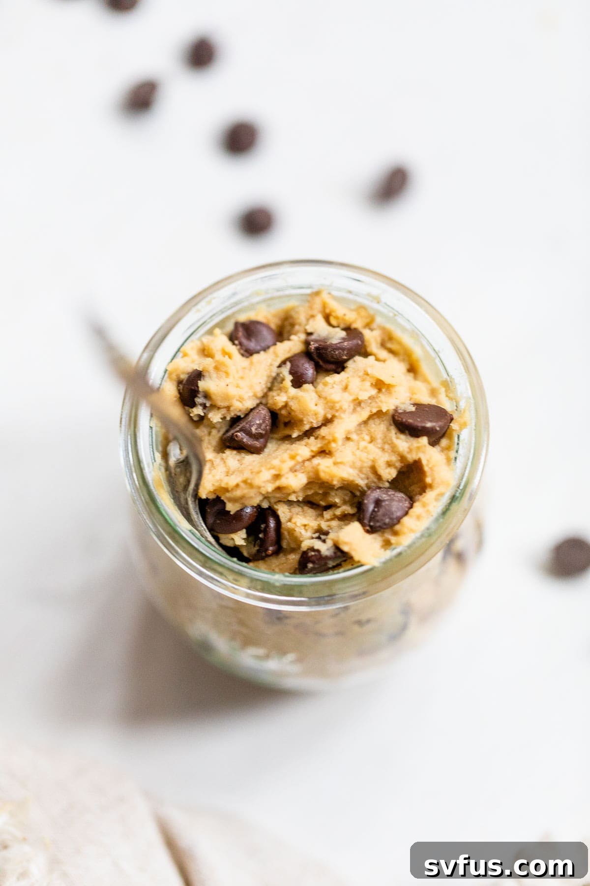 Small glass jar filled with layers of chickpea chocolate chip cookie dough, perfect for gifting or portion control.