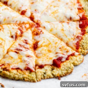 A whole cheese pizza on a piece of parchment paper, featuring a golden, crispy cauliflower crust.