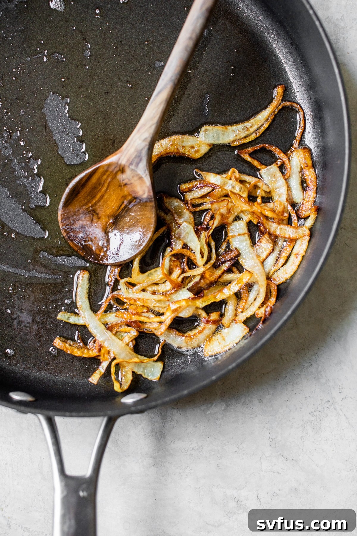 Sliced yellow onions simmering slowly in a skillet with melted butter, beginning to caramelize and turn golden-brown.
