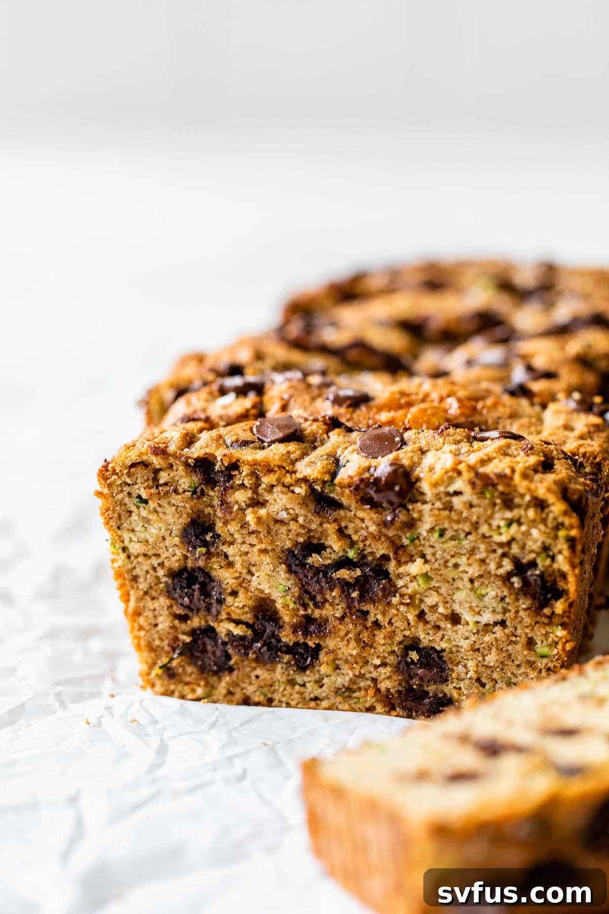 Sliced chocolate chip gluten-free zucchini bread on parchment paper