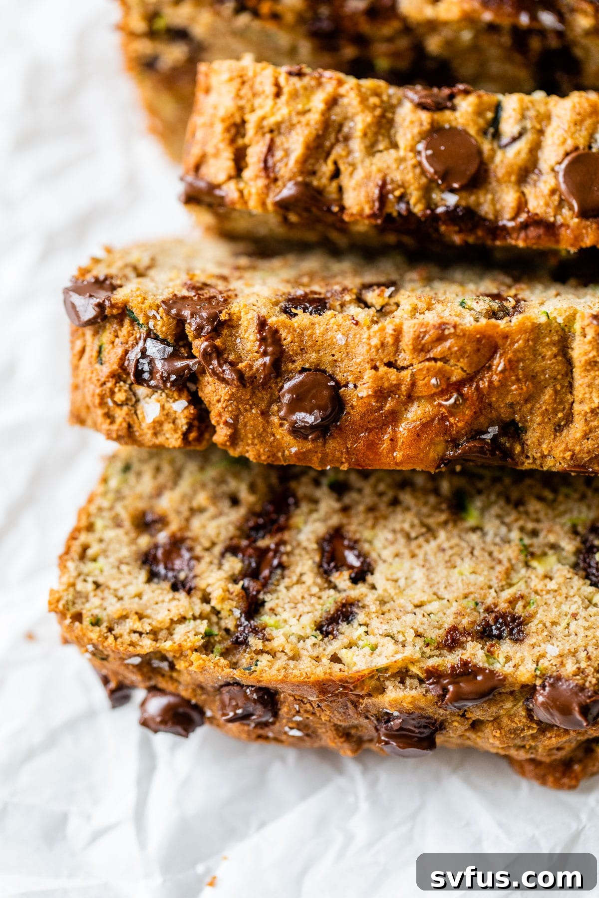 Sliced loaf of gluten-free zucchini bread with chocolate chips on parchment paper