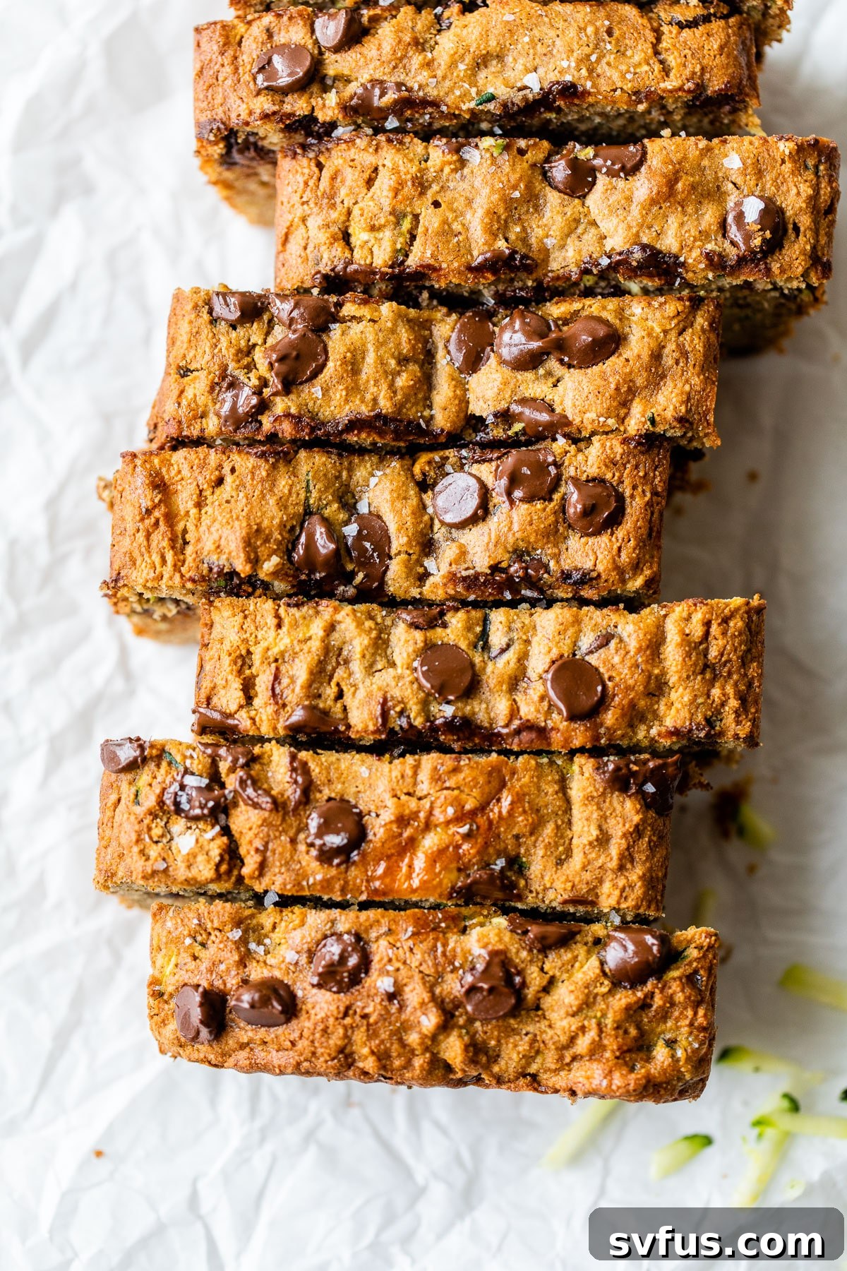 Close-up of a sliced gluten-free zucchini bread with chocolate chips on parchment paper