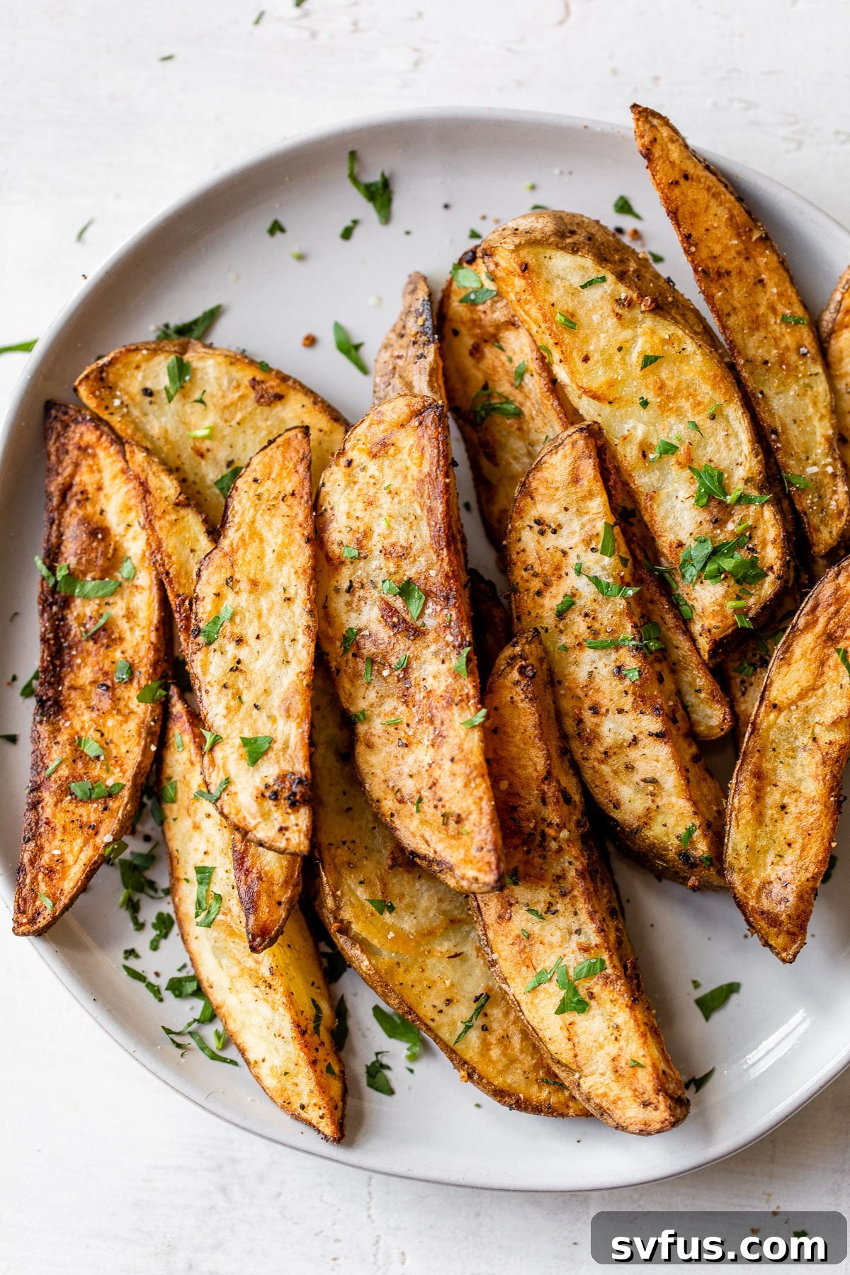 crispy seasoned potato wedges on a white plate