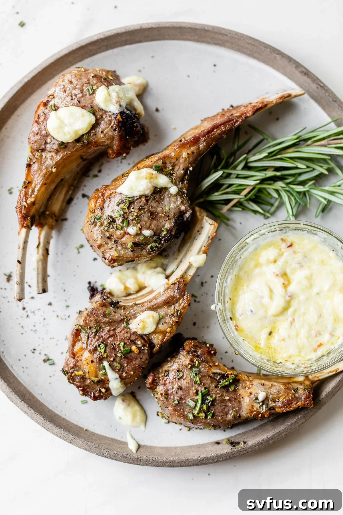 Four perfectly cooked air fryer lamb chops resting on a plate, garnished with fresh rosemary and a side of creamy aioli.