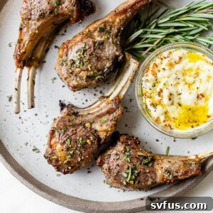 Cooked lamb chops plated with a small dish of aioli and fresh rosemary.