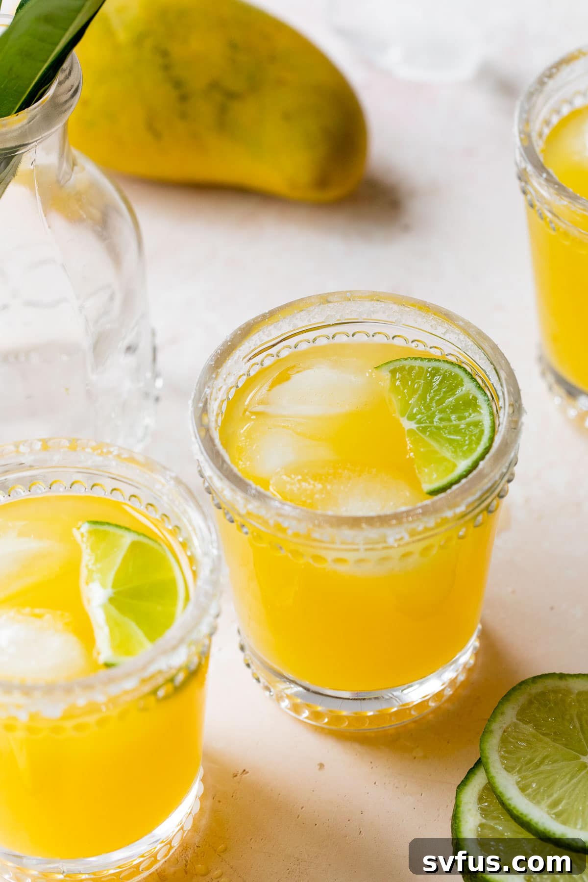 three glasses filled with mango juice and a lime wedge