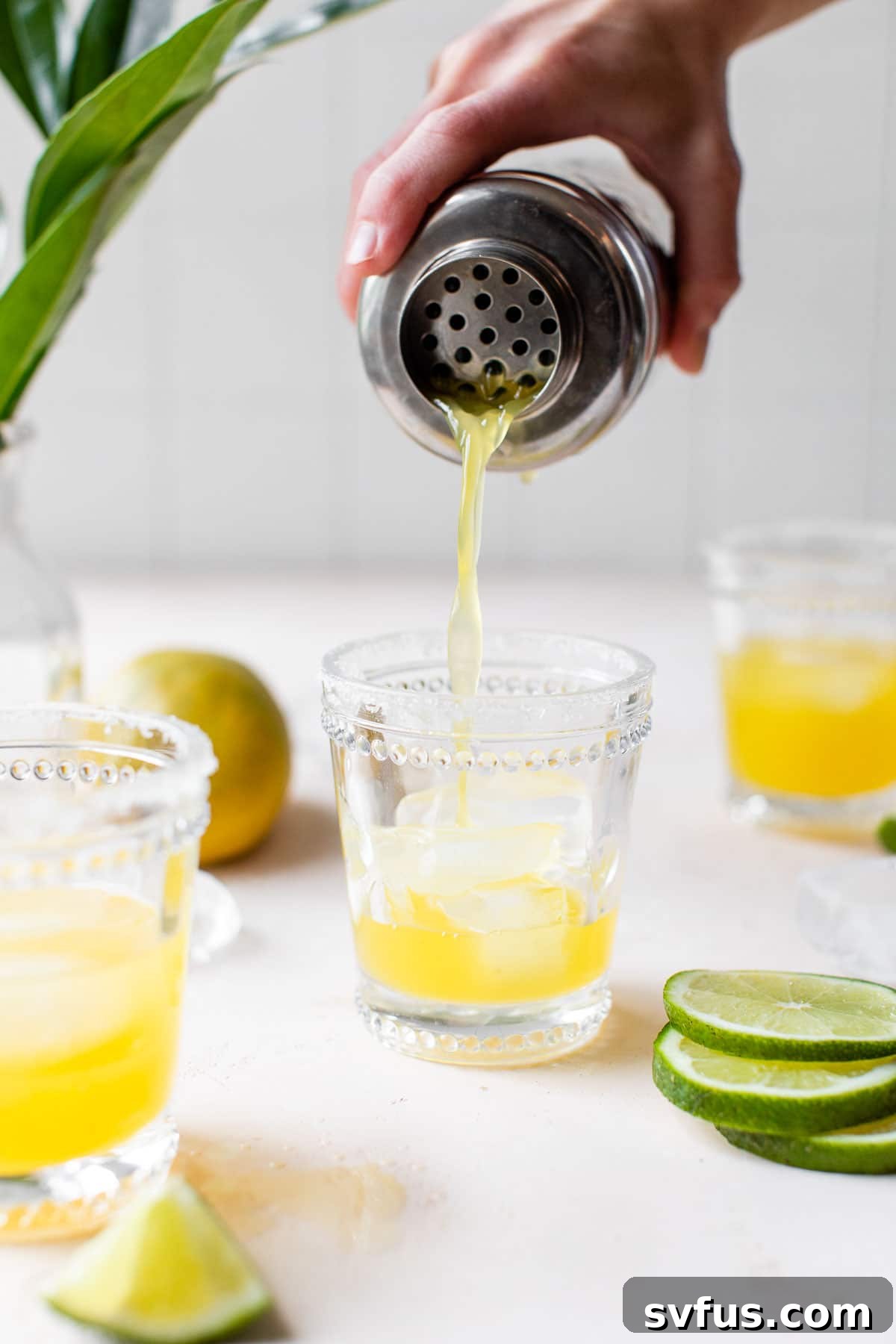someone pouring a cocktail into a glass