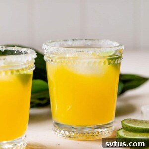 mango margarita in a glass with lime wedges