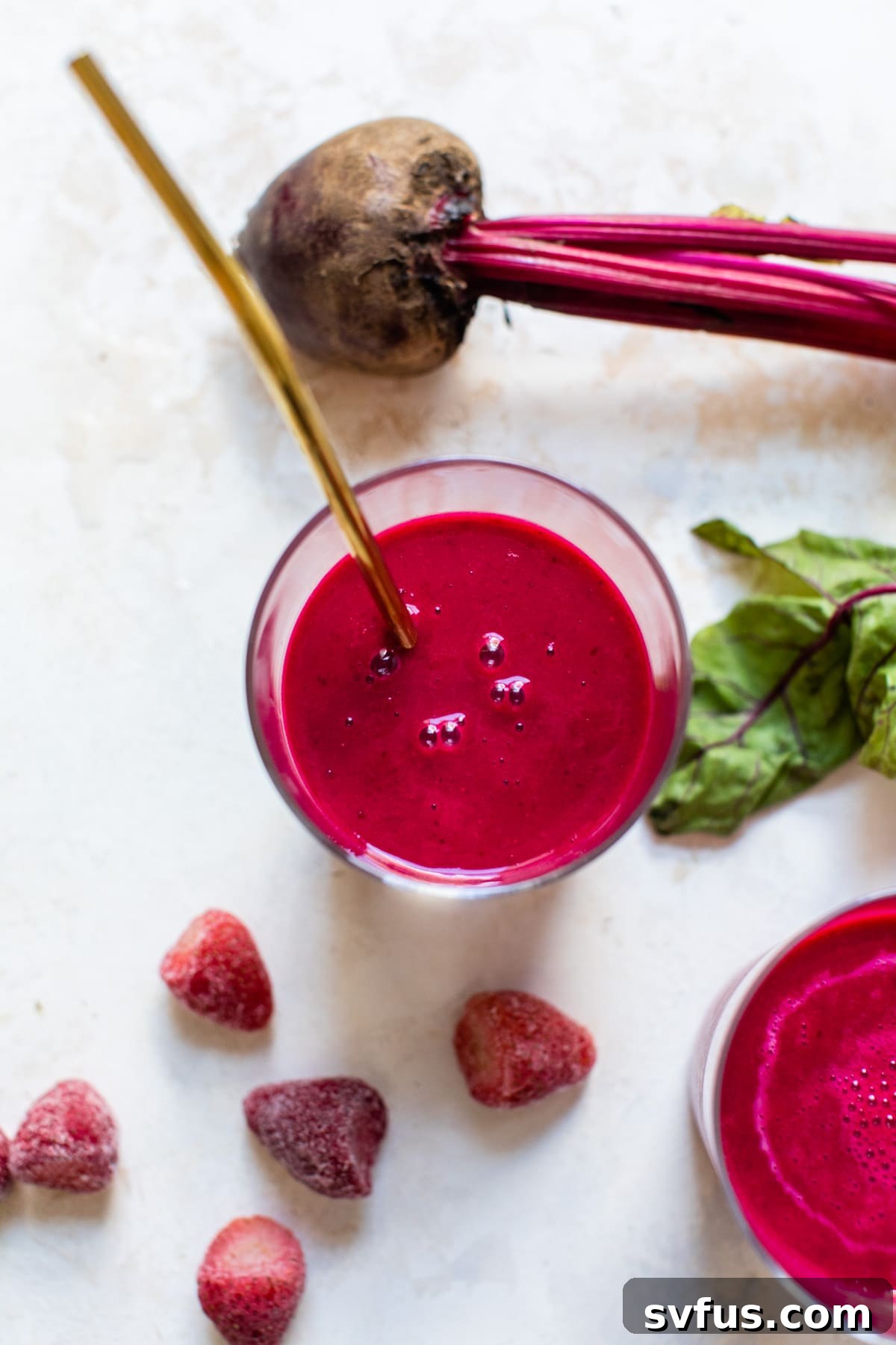 Close-up of a pink beet smoothie with a straw in a glass, on a light background.