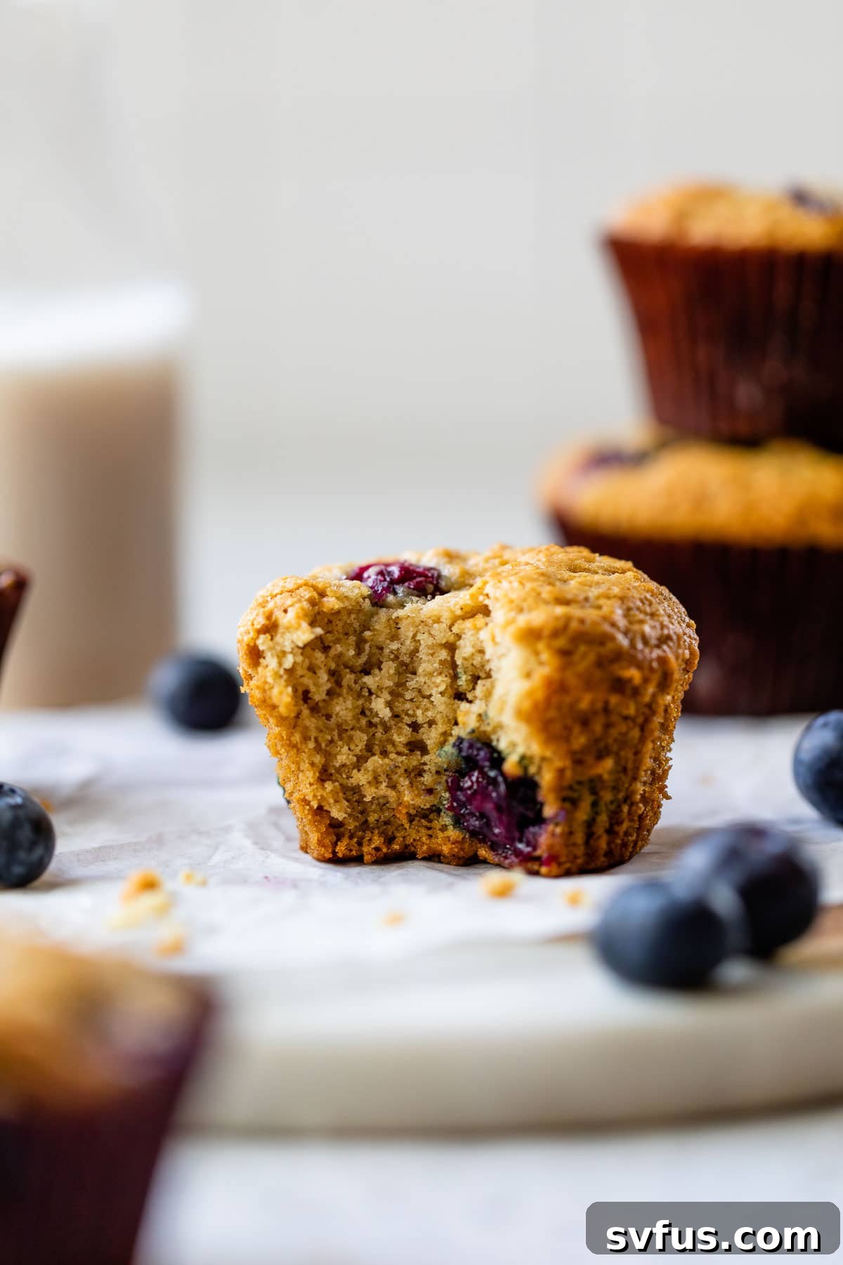 A delicious vegan blueberry muffin with a bite taken out, revealing its moist and fluffy interior.