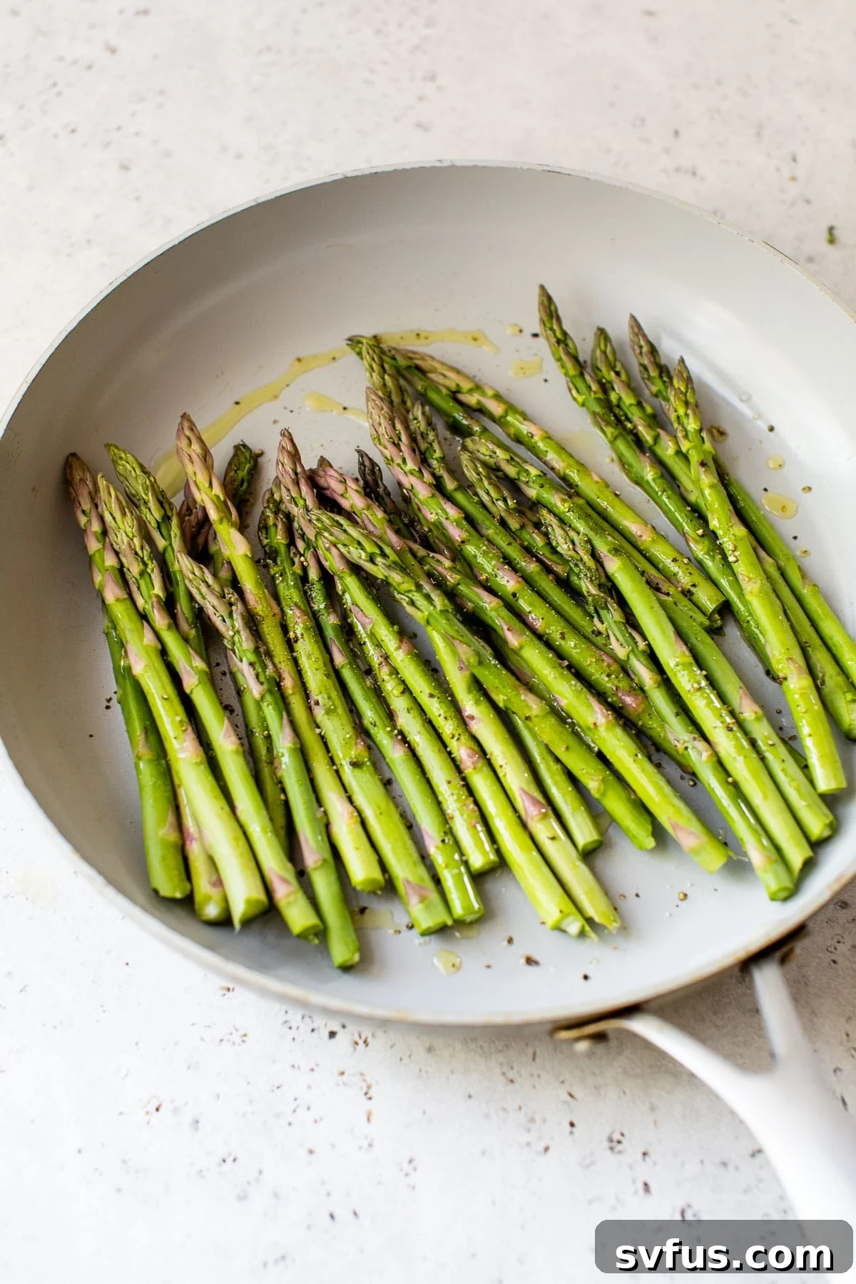 Fresh raw asparagus laid out in a cast iron skillet, ready for sautéing