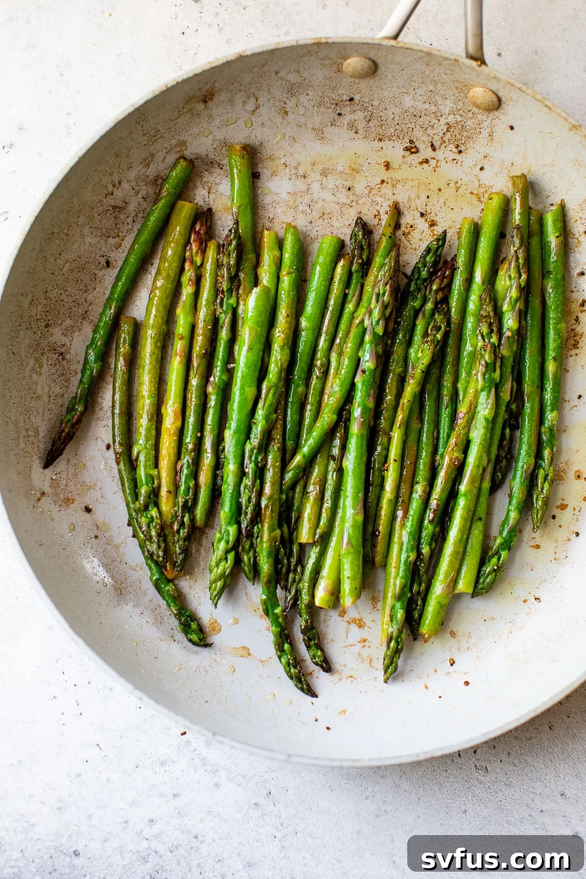 Close-up of perfectly cooked asparagus in a skillet, vibrant green and slightly charred