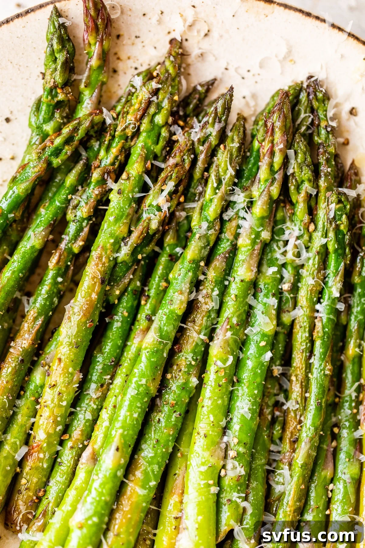 Close-up of cooked asparagus spears generously sprinkled with shredded Parmesan cheese