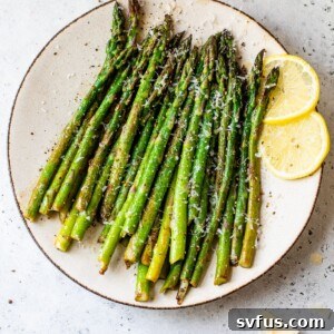 cooked asparagus on a plate with lemon wedges