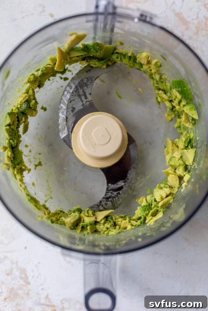 mashed avocado in a food processor, before other ingredients are added.