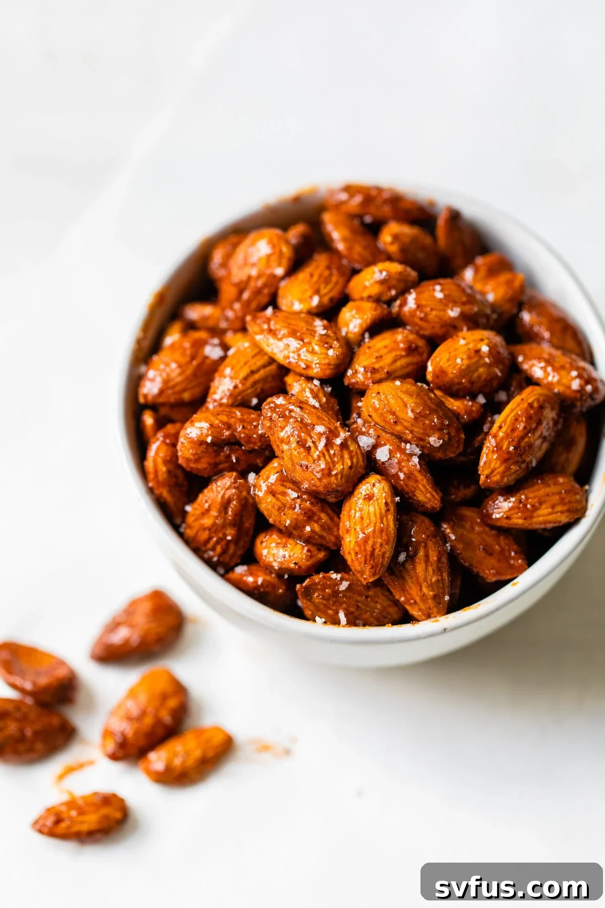 A bowl filled with freshly made Buffalo Spice Almonds, showcasing their rich, reddish-orange coating and inviting texture.