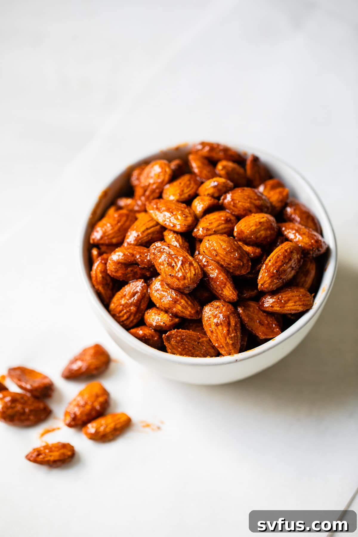 A close-up of a rustic wooden bowl filled with an abundance of perfectly coated Buffalo Spice Almonds, ready to be enjoyed.