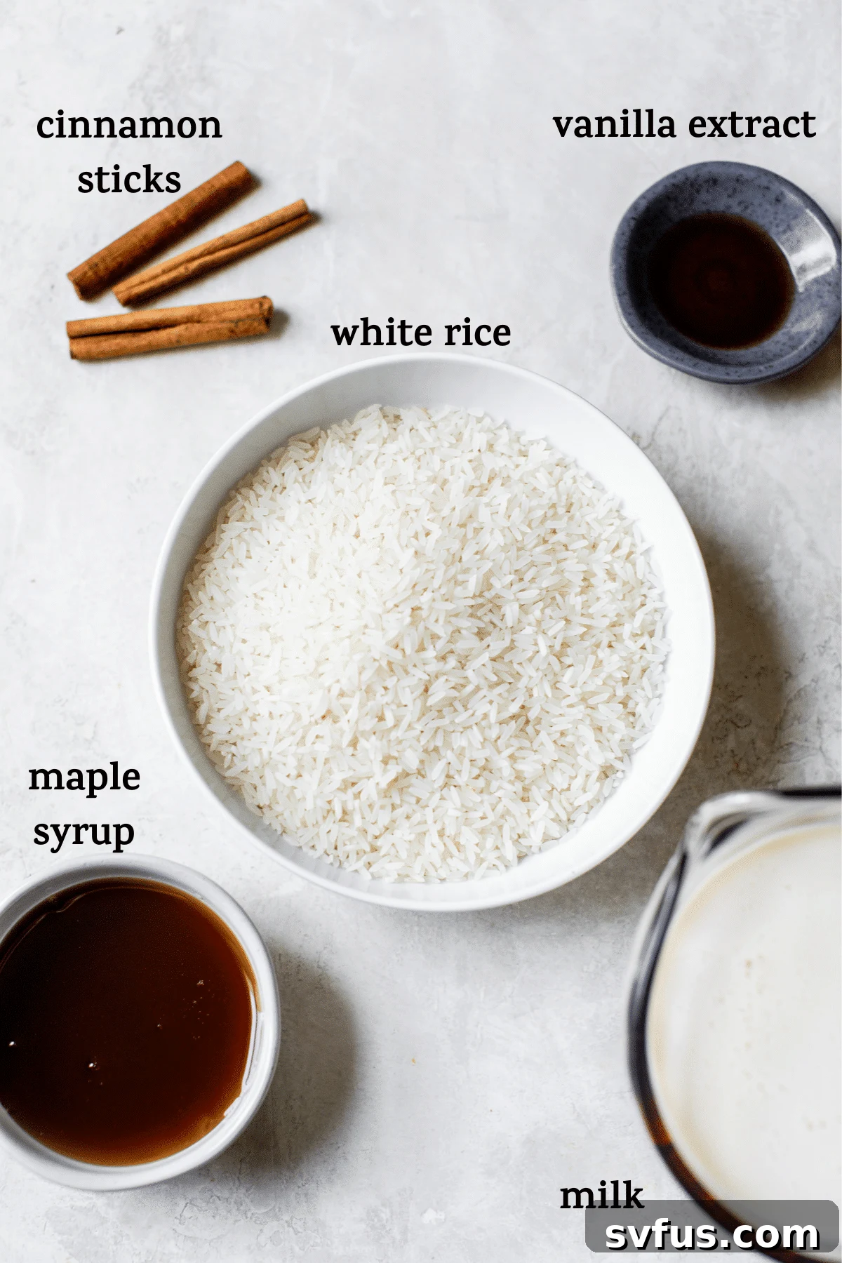 Arrangement of ingredients for Vegan Arroz con Leche including rice, milk, maple syrup, and cinnamon sticks, ready for cooking.