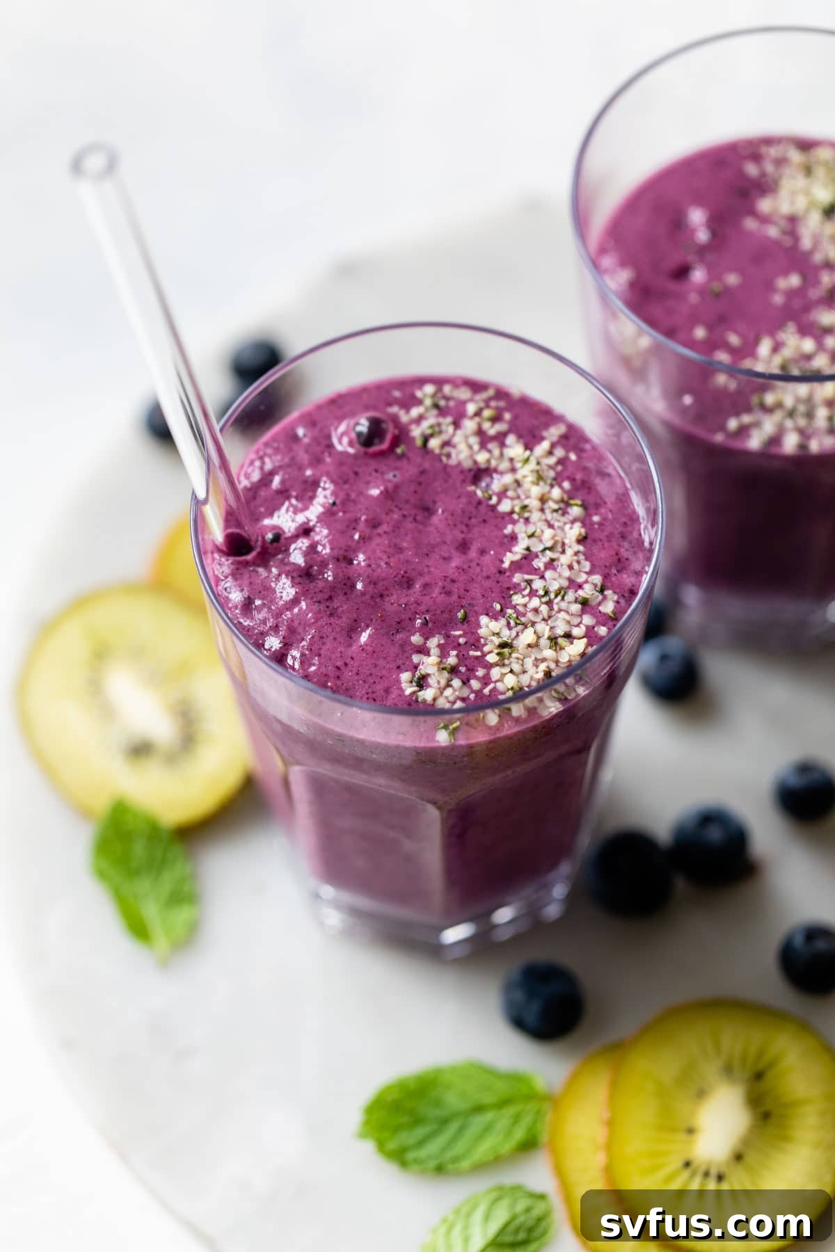 A refreshing blueberry kiwi smoothie in a glass, garnished with hemp seeds.