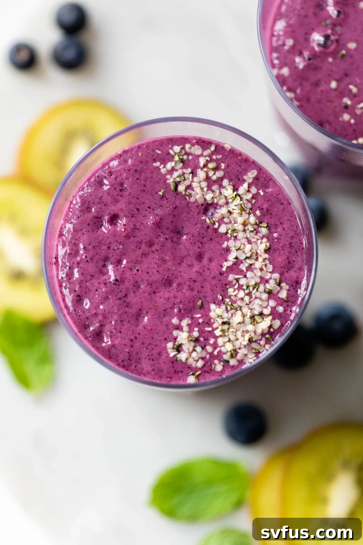 Overhead shot of a blueberry kiwi smoothie in a glass, with fresh kiwi slices next to it.