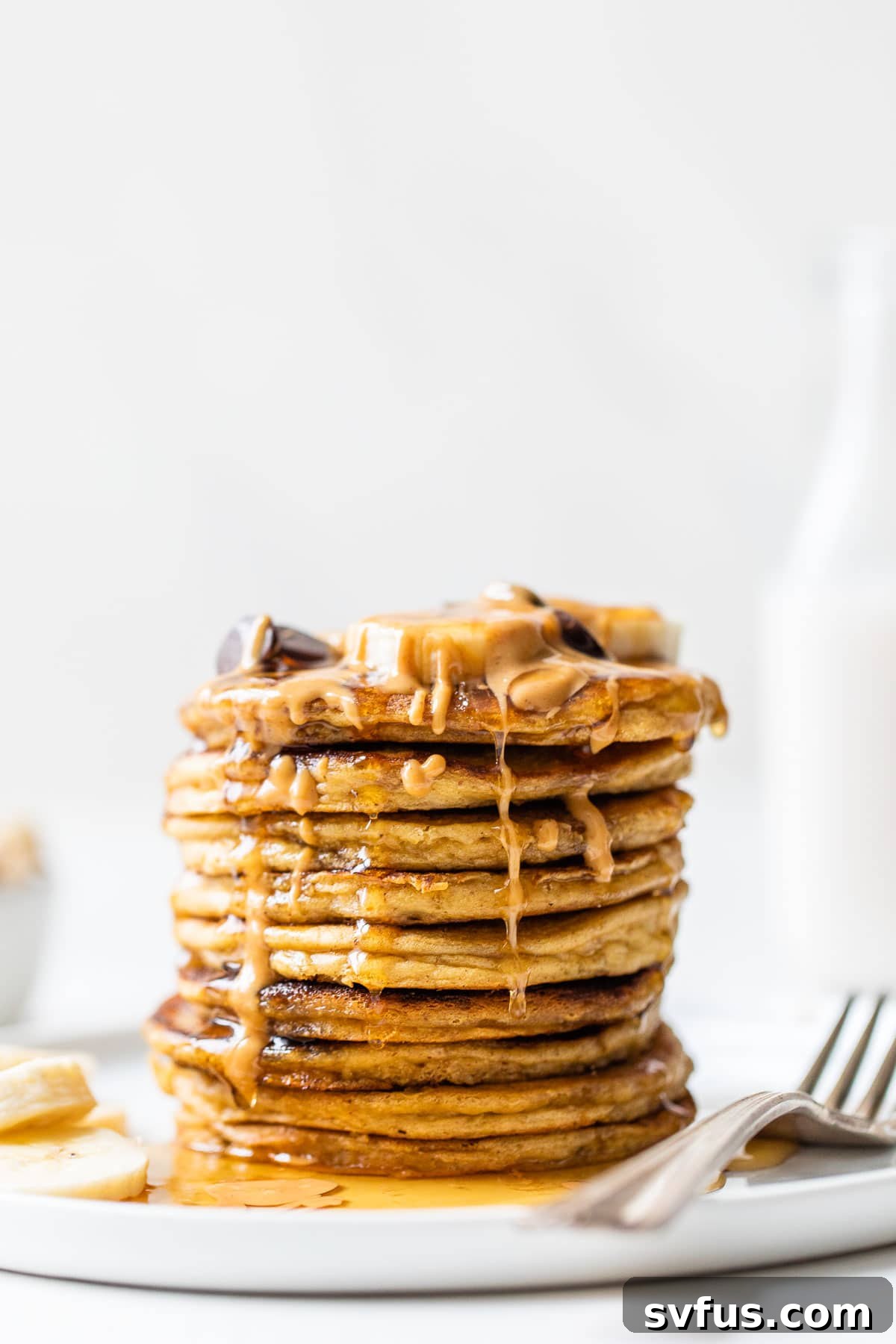 A beautifully stacked plate of flourless chickpea pancakes, generously drizzled with rich peanut butter and golden maple syrup, ready to be enjoyed as a wholesome breakfast.