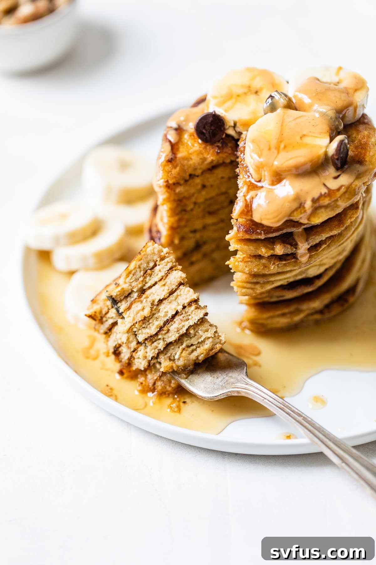 A close-up of a stack of flourless chickpea pancakes on a plate, with a bite taken out of the top pancake, showing its fluffy interior and inviting texture.