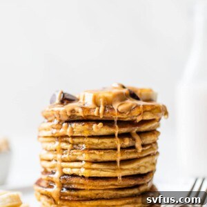 stack of pancakes on a plate with peanut butter and maple syrup